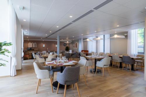 une salle à manger avec tables, chaises et fenêtres dans l'établissement Résidence de Troyes, à Troyes