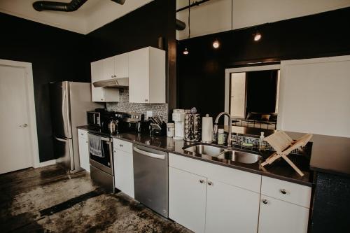 a kitchen with white cabinets and a sink and a refrigerator at The Downtown Bungalow Loft in Memphis