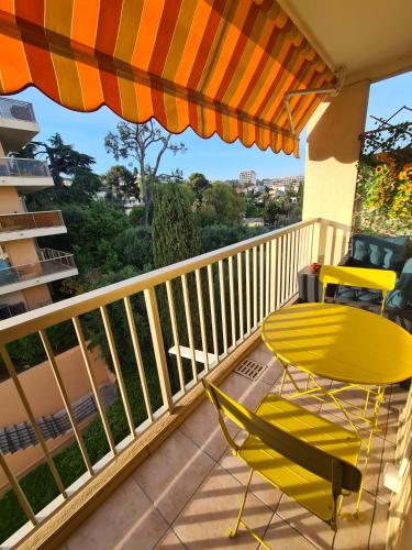 une chaise jaune et un parasol sur un balcon dans l'établissement STUDIO BALCON CALME AVEC PARKING 5mn de la MER, à Nice