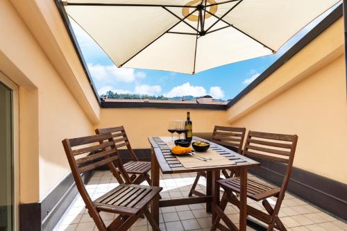 a table and chairs on a balcony with an umbrella at Modern Apartment with double terrace and parking in Alba