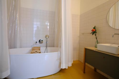 eine weiße Badewanne im Bad mit Waschbecken in der Unterkunft Cravo’s Heritage House in Pinhel