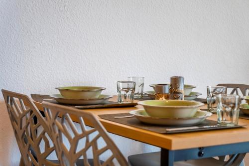 a wooden table with plates and bowls and glasses on it at Apolo XI, Calpe, Modern Holiday Apartment, Sea view, Pool, 100m to Beach! in Calpe