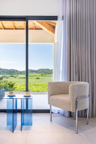 a chair and a glass table in front of a window at Royal Tiki Lodges - Maison d'hôtes avec Piscine chauffée Jacuzzi- Chambres ou Villa entière - Villa SCL in Plaissan