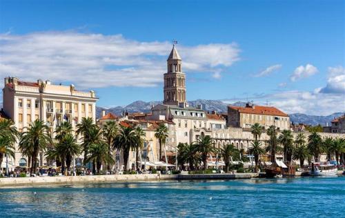 a city with palm trees and a building with a clock tower at Apartment Moona udaljen 10 min setnje od Palace, Rive i plaze in Razvala