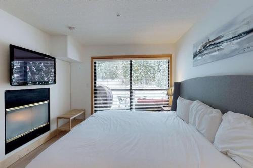 a bedroom with a white bed and a flat screen tv at Powderhorn by Whistler Blackcomb Vacation Rentals in Whistler