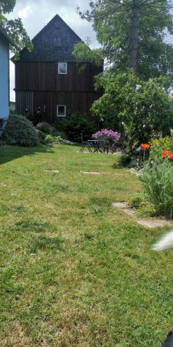 a yard with a house and a table and flowers at Ferienhaus Villa Zauberblick am Rennsteig Frankenwald in Ludwigsstadt