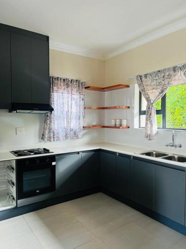 a kitchen with black cabinets and a sink at Self Catering 2 Bedroom Apartment in Matsapha