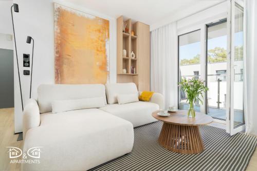 een woonkamer met een witte bank en een tafel bij Zielona 16 D&D Apartments in Międzywodzie