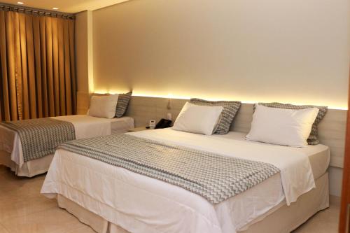 a hotel room with two beds with white sheets at Hotel Relicário in Araguaína
