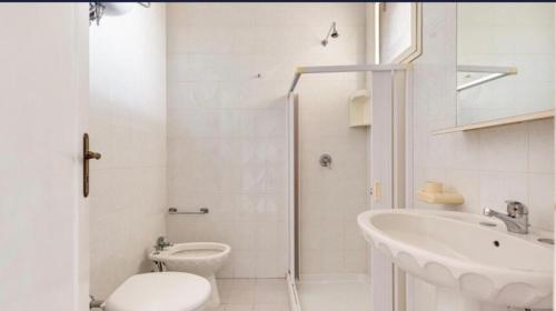 a white bathroom with a toilet and a sink at ASIA PP Sx in Torre Lapillo