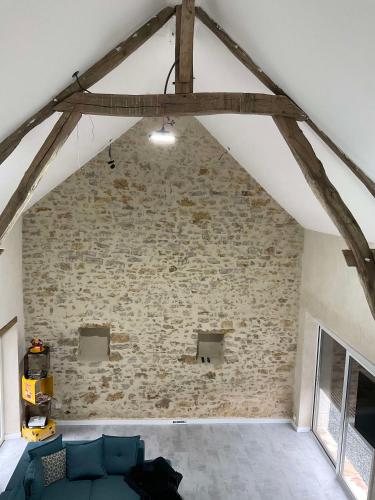 a room with a stone wall and a blue couch at BERRY's CHARM in Le Pêchereau