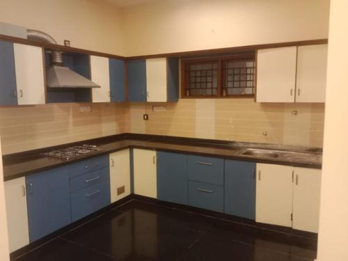 een keuken met blauwe en witte kasten en een wastafel bij Royal Residency in Tiruvannamalai