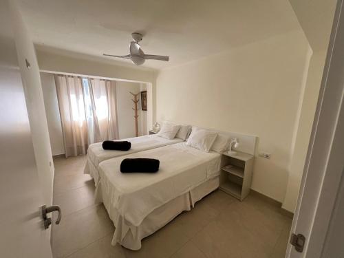 a bedroom with a white bed with a ceiling fan at Precioso apartamento de 2 habitaciones recién reformado en Benidorm in Benidorm