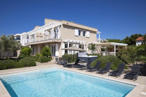 a villa with a swimming pool in front of a house at Villa BELLA - beautiful and modern house with pool, souna, jacuzzi & playground, Ližnjan - Istra in Ližnjan
