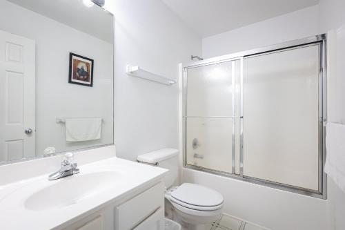a white bathroom with a shower and a toilet at Semi Ocean Front Luxury Home Pool Spa Game Room in Duck
