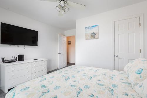 a bedroom with a bed and a flat screen tv at Semi Ocean Front Luxury Home Pool Spa Game Room in Duck