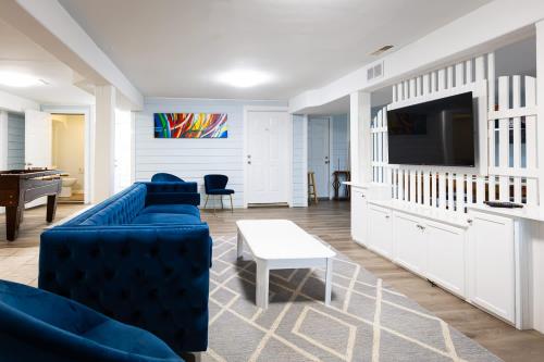 a living room with a blue couch and a tv at Semi Ocean Front Luxury Home Pool Spa Game Room in Duck