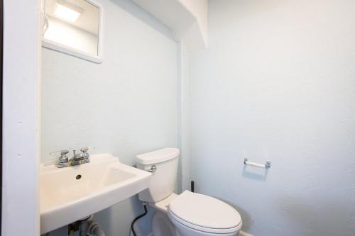 a white bathroom with a toilet and a sink at Semi Ocean Front Luxury Home Pool Spa Game Room in Duck