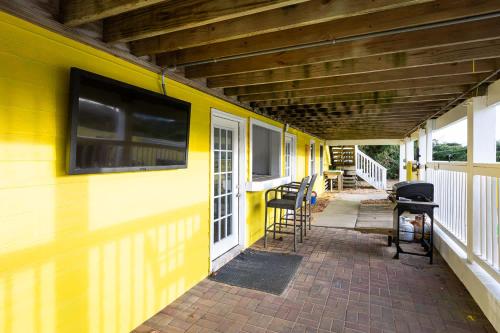 a yellow building with chairs on a porch at Semi Ocean Front Luxury Home Pool Spa Game Room in Duck