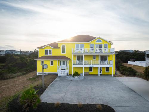 a yellow house on a hill with a driveway at Semi Ocean Front Luxury Home Pool Spa Game Room in Duck