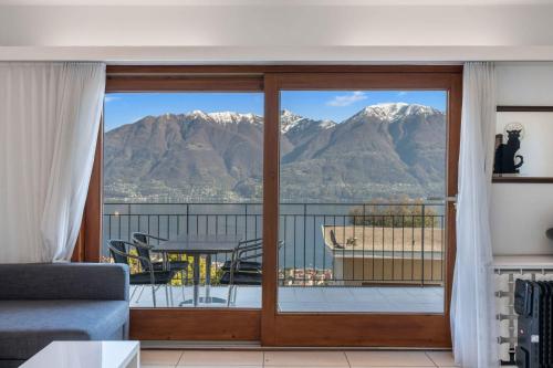 a room with a balcony with a view of mountains at Pendio del Sole App 3838 in Orselina