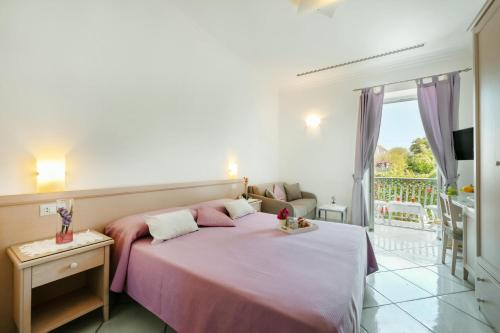 una camera con letto rosa e balcone di La Vispa Teresa a Ischia