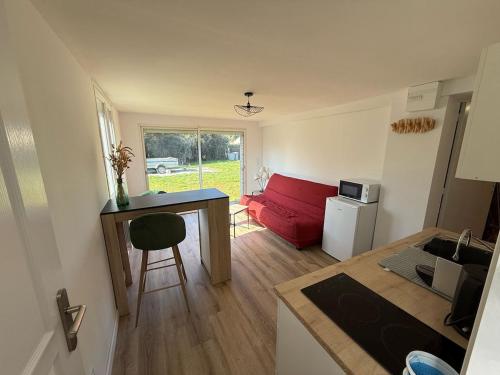 Il comprend une petite cuisine et un salon avec un canapé rouge. dans l'établissement Appartement type 2 à corné, à Corné