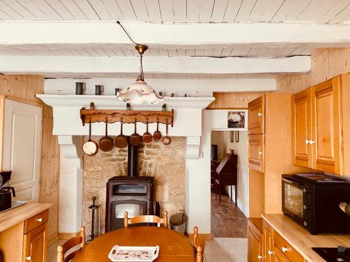 une cuisine avec une table en bois et une cheminée dans l'établissement La Chtite Campagnarde de Saône, 