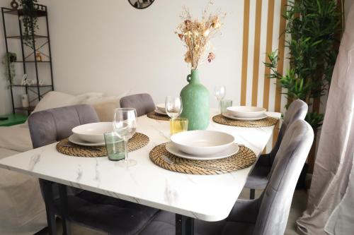 une table de salle à manger avec des assiettes et des verres dessus dans l'établissement Charming 2 bedrooms free parking- near paris st lazare, à Argenteuil