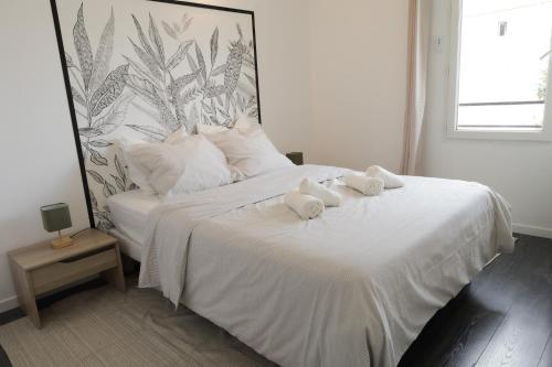 une chambre avec un lit blanc avec des serviettes dessus dans l'établissement Charming 2 bedrooms free parking- near paris st lazare, à Argenteuil