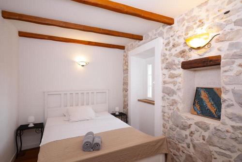 ein Schlafzimmer mit einem Bett und einer Steinwand in der Unterkunft Hello Sunshine in Veli Iž