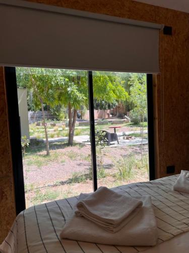 a bed with two towels on it in front of a window at La Misión Tiny Houses in Ciudad Lujan de Cuyo