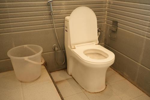 a bathroom with a toilet and a trash can at 11 Leaf Hotel in Bhubaneshwar