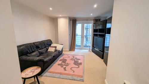 a living room with a black leather couch and a television at Beautiful and Central Apartment in Newcastle City in Central Station