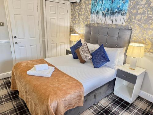a small bedroom with a bed with blue pillows at 4 Sisters Inn in Theydon Bois