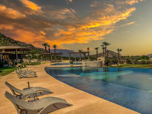 una piscina del resort con sedie e palme di Stylish Summer 2BR Retreat w Pool & Beach Access a Ensenada Blanca