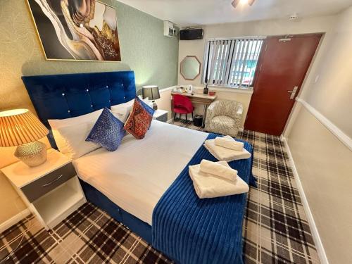a bedroom with a large bed with a blue headboard at 4 Sisters Inn in Theydon Bois