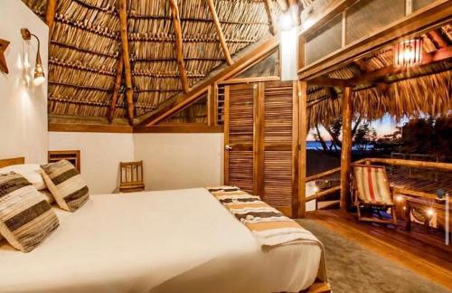 a bedroom with a large bed with a straw roof at Casitas Pacific in Popoyo
