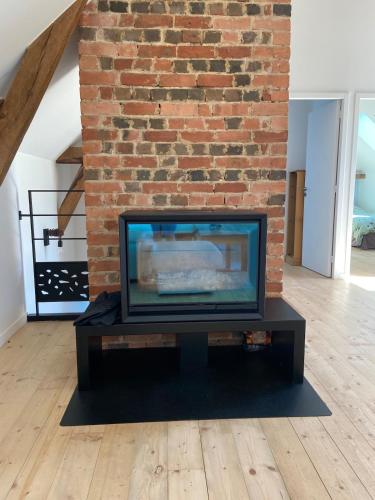 a flat screen tv sitting in front of a brick wall at Gite 8-10 pers, 4 chambres, billard, jardin in La Bouexière