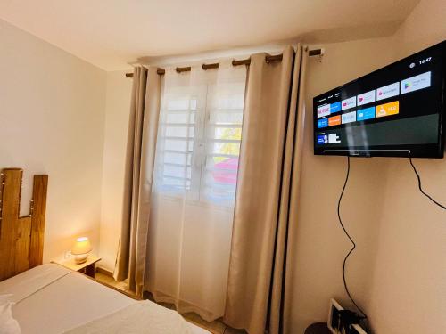 a bedroom with a flat screen tv on the wall at Appartement Cosy La Vanille 1 in Ducos