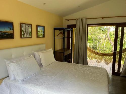 a bedroom with a white bed and a sliding glass door at Refúgio By Bellatrix Ecolodge in Mata de Sao Joao