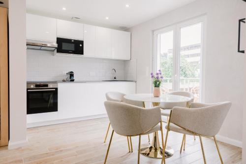 une cuisine blanche avec une table et des chaises blanches dans l'établissement Amour et spa prestige à Honfleur, à Honfleur