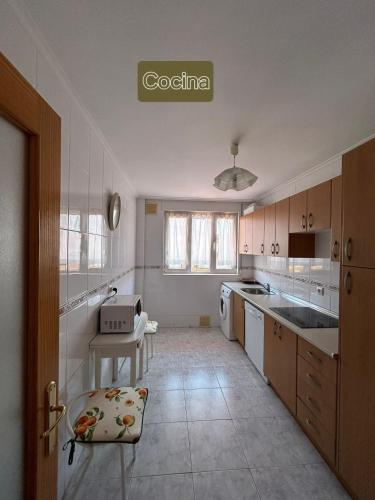 a large white kitchen with a counter and a table at Ático con Terraza en Isla in Isla