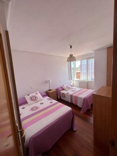 two beds in a room with pink and white sheets at Ático con Terraza en Isla in Isla