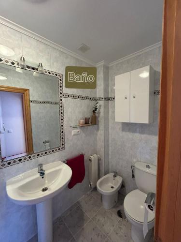 a bathroom with a sink and a toilet and a mirror at Ático con Terraza en Isla in Isla