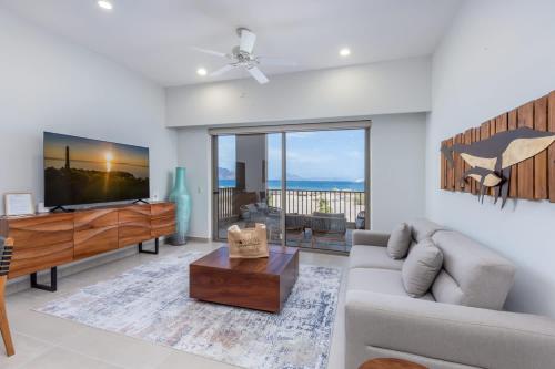 Una sala de estar con un sofá y un televisor. en Danzante Bay Oceanfront 2 BR Beach & Golf, en Ensenada Blanca