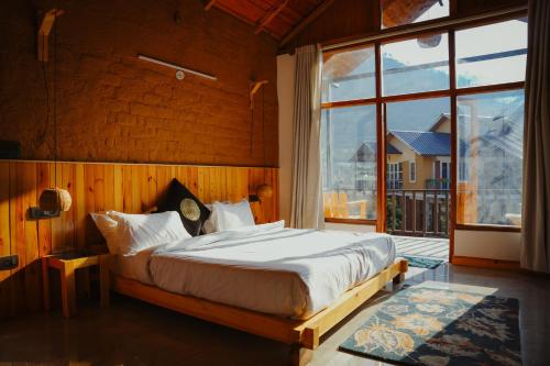 a bedroom with a bed and a large window at Ethnic Trail Homestay in Bhīm Tāl