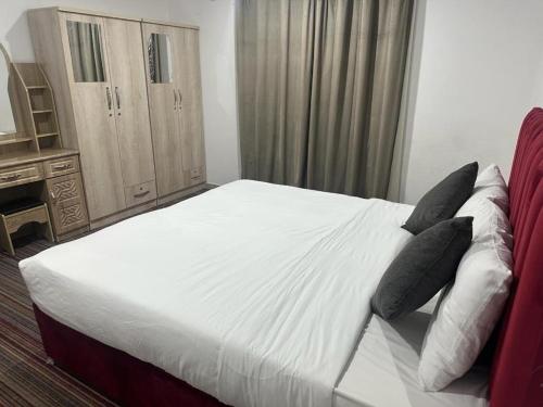a bedroom with a white bed with black pillows at Pyramiza Fahaheel بيراميزا الفحيحيل in Kuwait