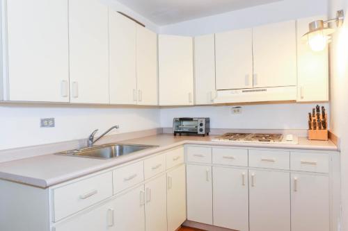 a white kitchen with white cabinets and a sink at Villa Sessions Entire House in Isabela