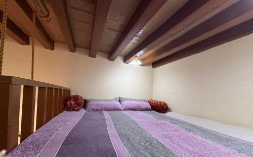 a bed in a room with purple sheets at Landour Apartment Beauty and Charm Kothri- Vintage Vibes in Mussoorie